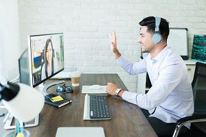 man waving to other coworkers during virtual meeting