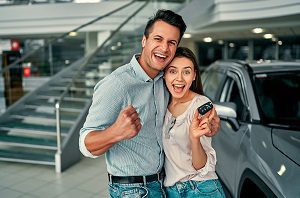 happy couple holding keys to new car
